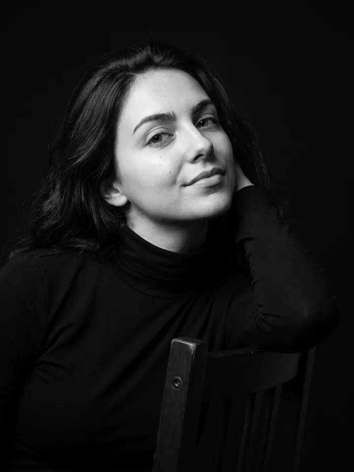 Black-and-white studio portrait of a person leaning on a chair