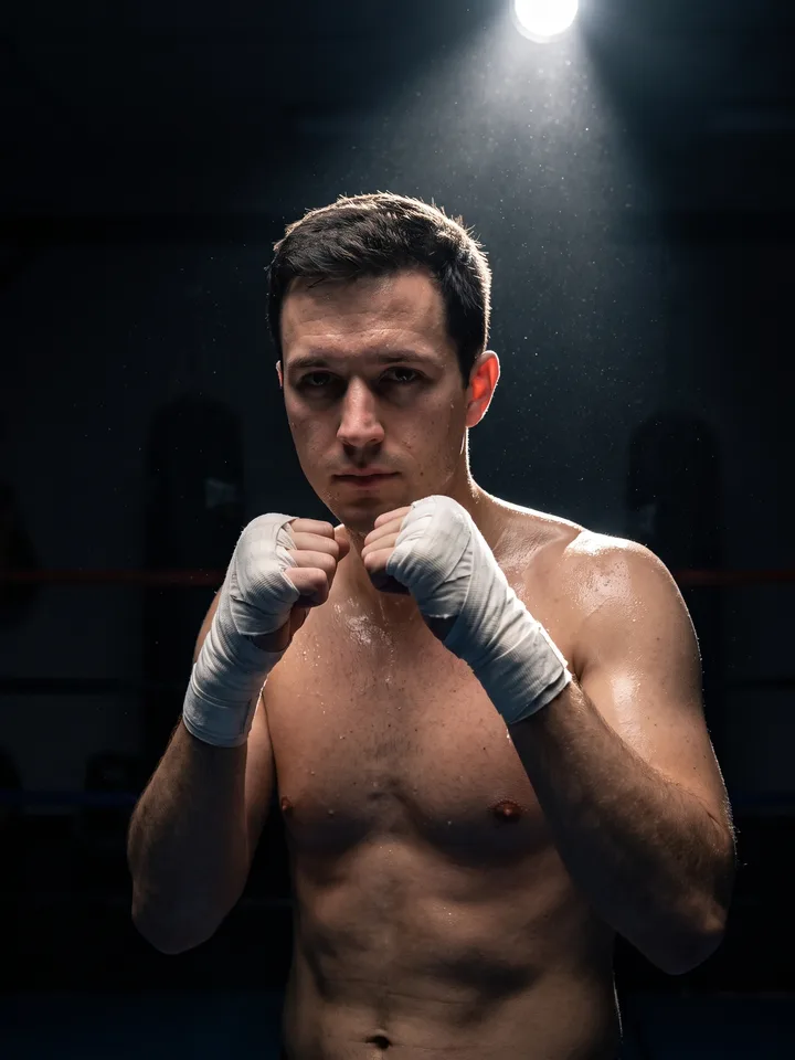 Boxer before a fight in a dark gym, hands wrapped in tape