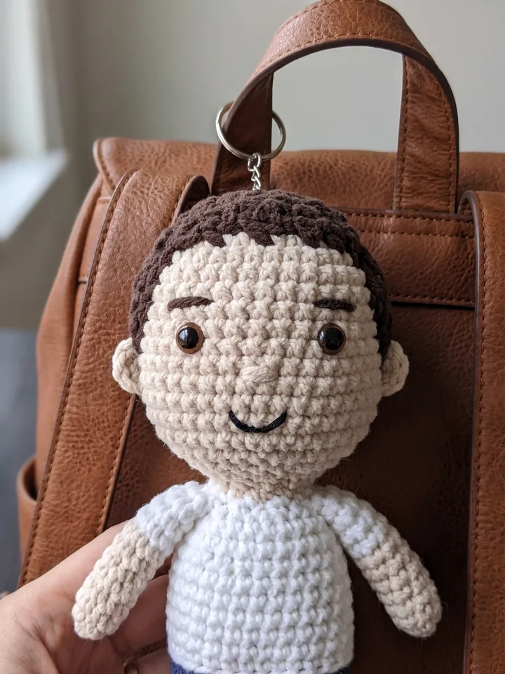 Crocheted plush keychain of the man hanging on a bag strap
