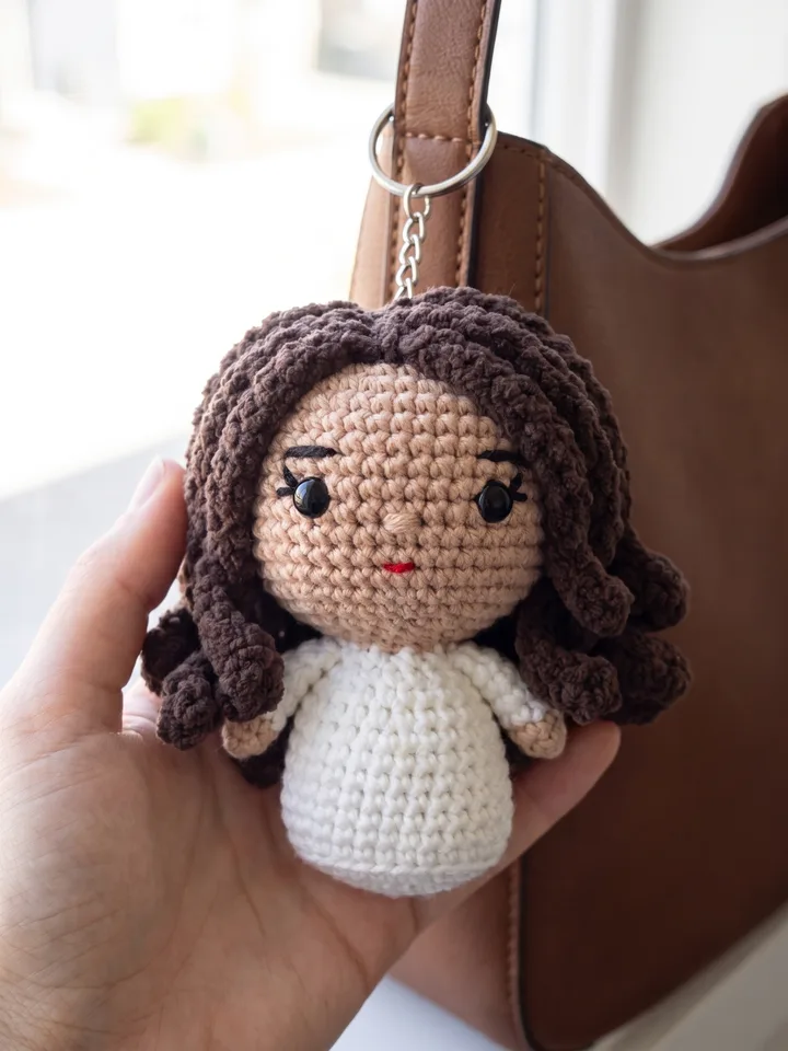 Crocheted plush keychain of the person hanging on a bag strap